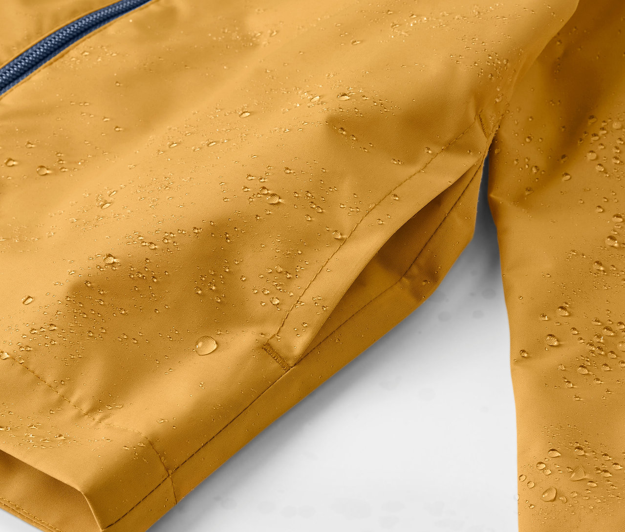 Gros plan sur une veste de pluie jaune pour enfant avec des gouttes d'eau.
