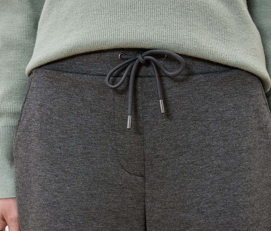 Gros plan d'une femme portant un pantalon de survêtement gris et un pull vert menthe.