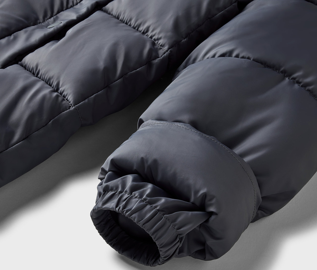 Gros plan sur une doudoune grise avec un poignet élastique.