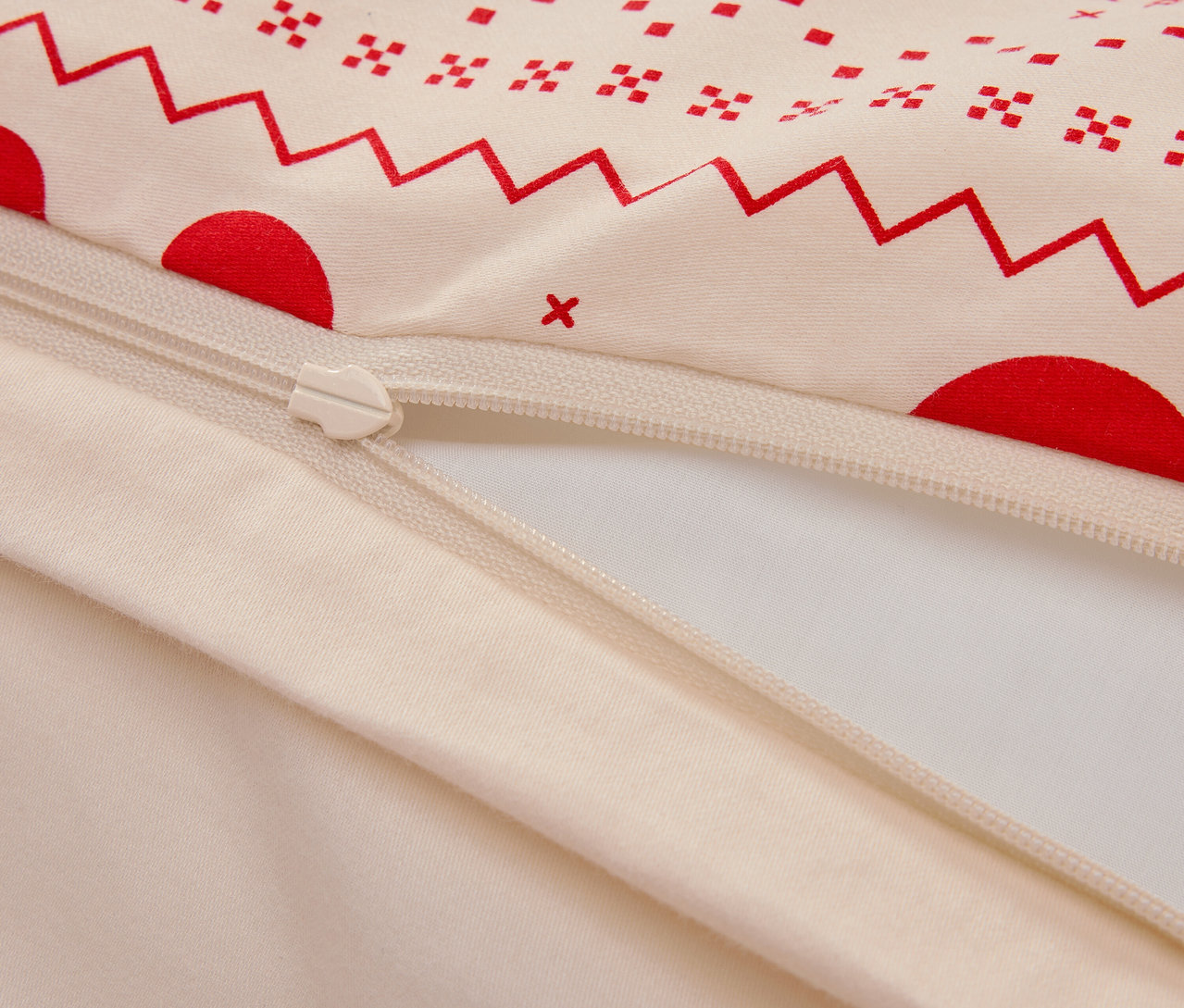 Gros plan d'une housse de couette en coton avec un motif géométrique rouge et une fermeture éclair.