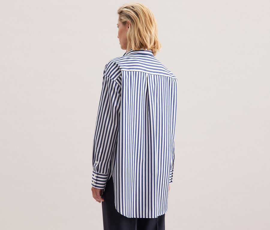 Femme blonde vue de dos portant une blouse-chemise grande taille rayée Seidensticker.