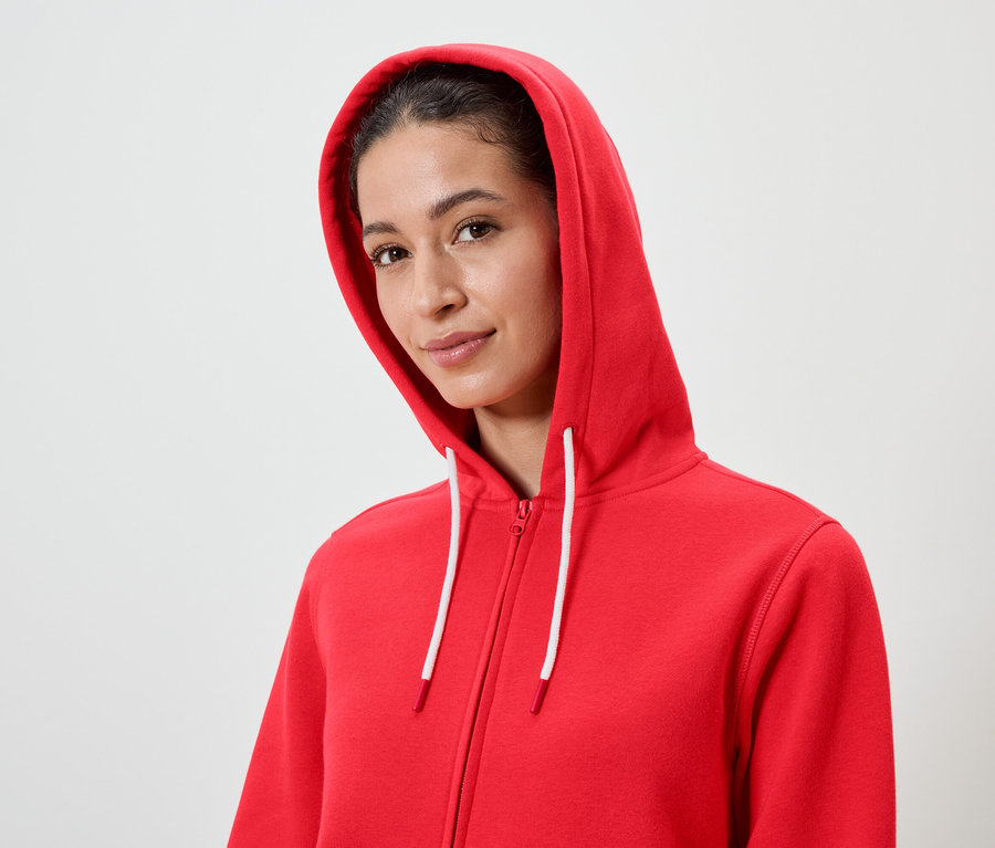 Portrait d'une femme aux cheveux bruns portant un sweat à capuche rouge avec des cordons blancs.