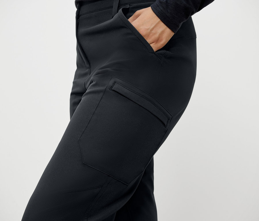Gros plan d'une femme portant un pantalon noir avec des poches et une main dans la poche.