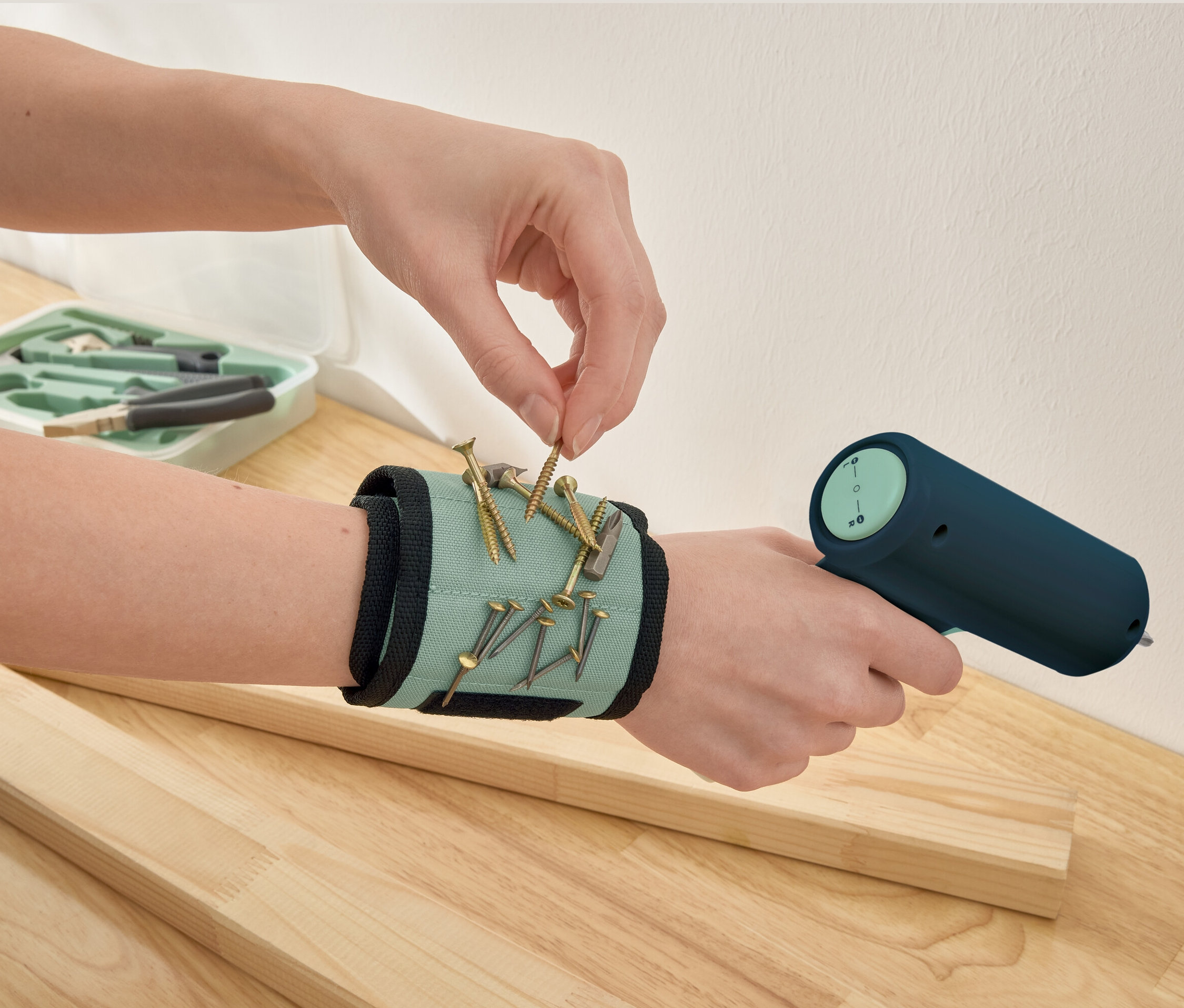 Une main ramasse une vis sur un bracelet magnétique.