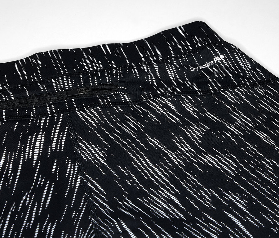 Gros plan sur un legging noir avec un motif de lignes blanches et une poche zippée.