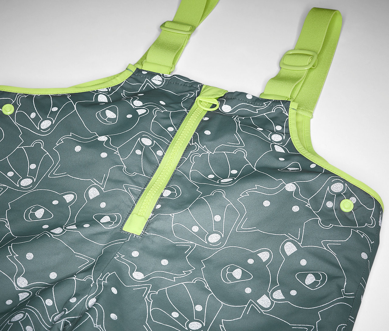 Détail d'un pantalon de pluie thermique pour enfants avec éléments réfléchissants, gris avec imprimé ours et renard et bretelles jaunes.