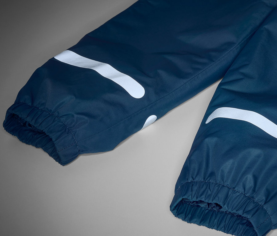 Gros plan sur un pantalon de pluie thermique pour enfant avec des réflecteurs.