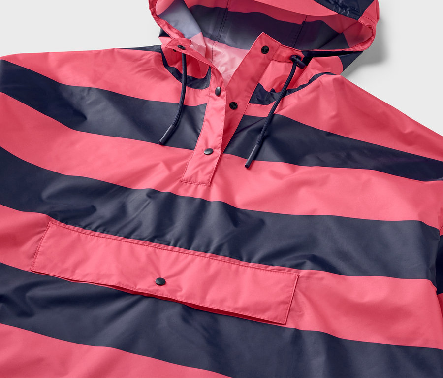 Gros plan sur un poncho de pluie rose et bleu marine à rayures avec une capuche et une poche.