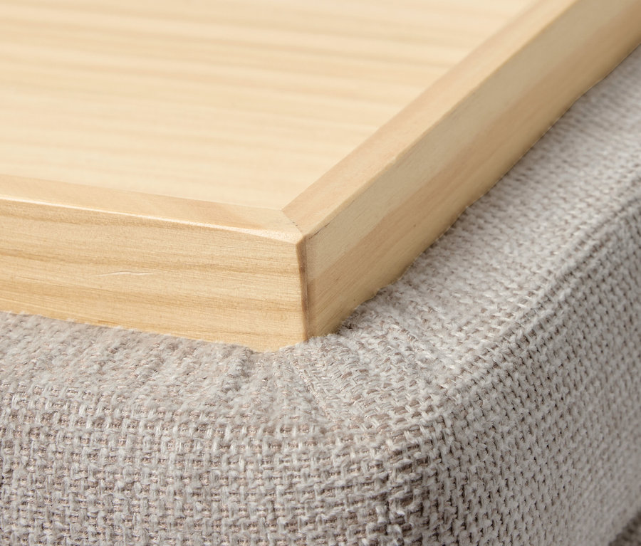 Gros plan d'un plateau en bois sur un pouf gris.