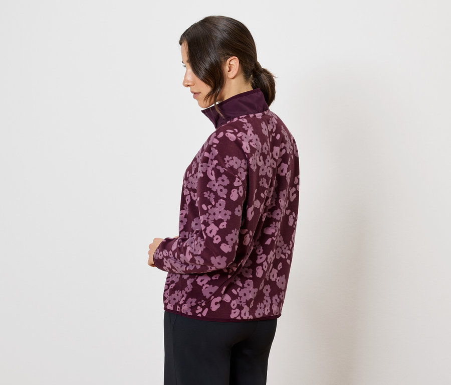 Femme de profil portant une veste bordeaux à motif floral.