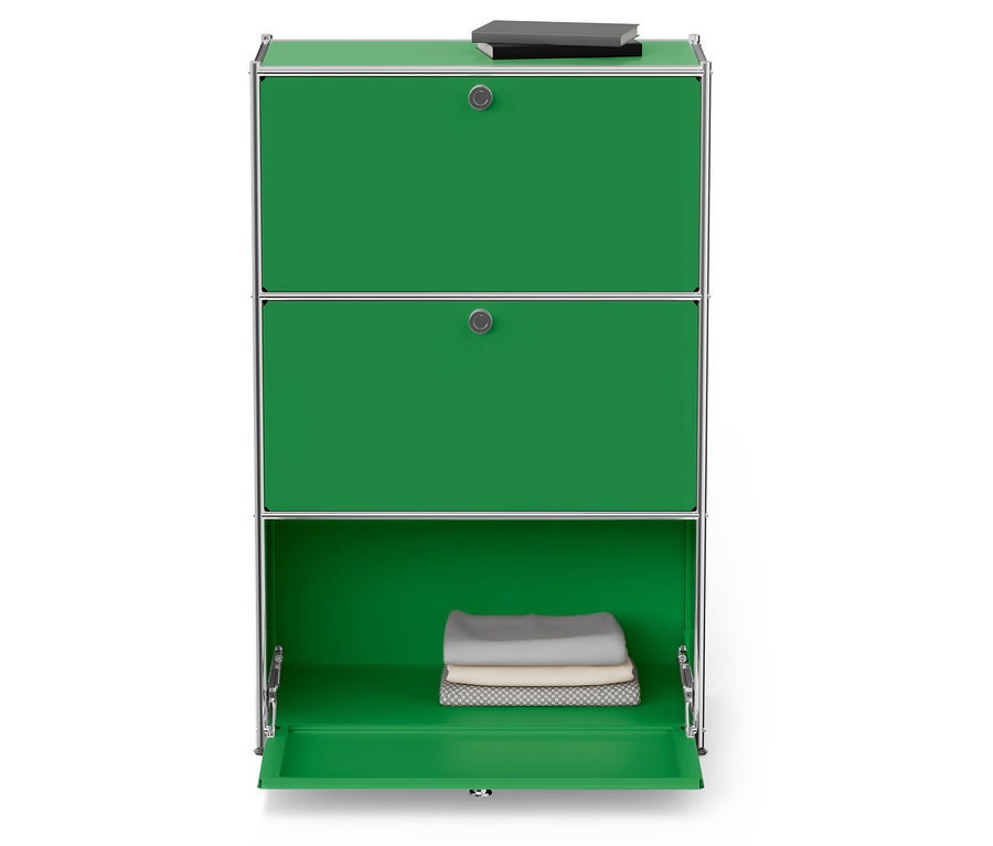 Une armoire verte avec trois compartiments, les deux supérieurs sont fermés, un livre est posé sur le compartiment supérieur, le compartiment inférieur est ouvert et contient des serviettes pliées.