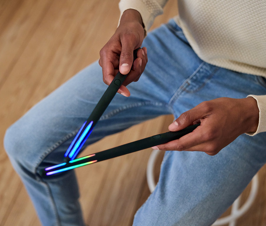 Un homme tient deux bâtons noirs avec des lumières aux extrémités.