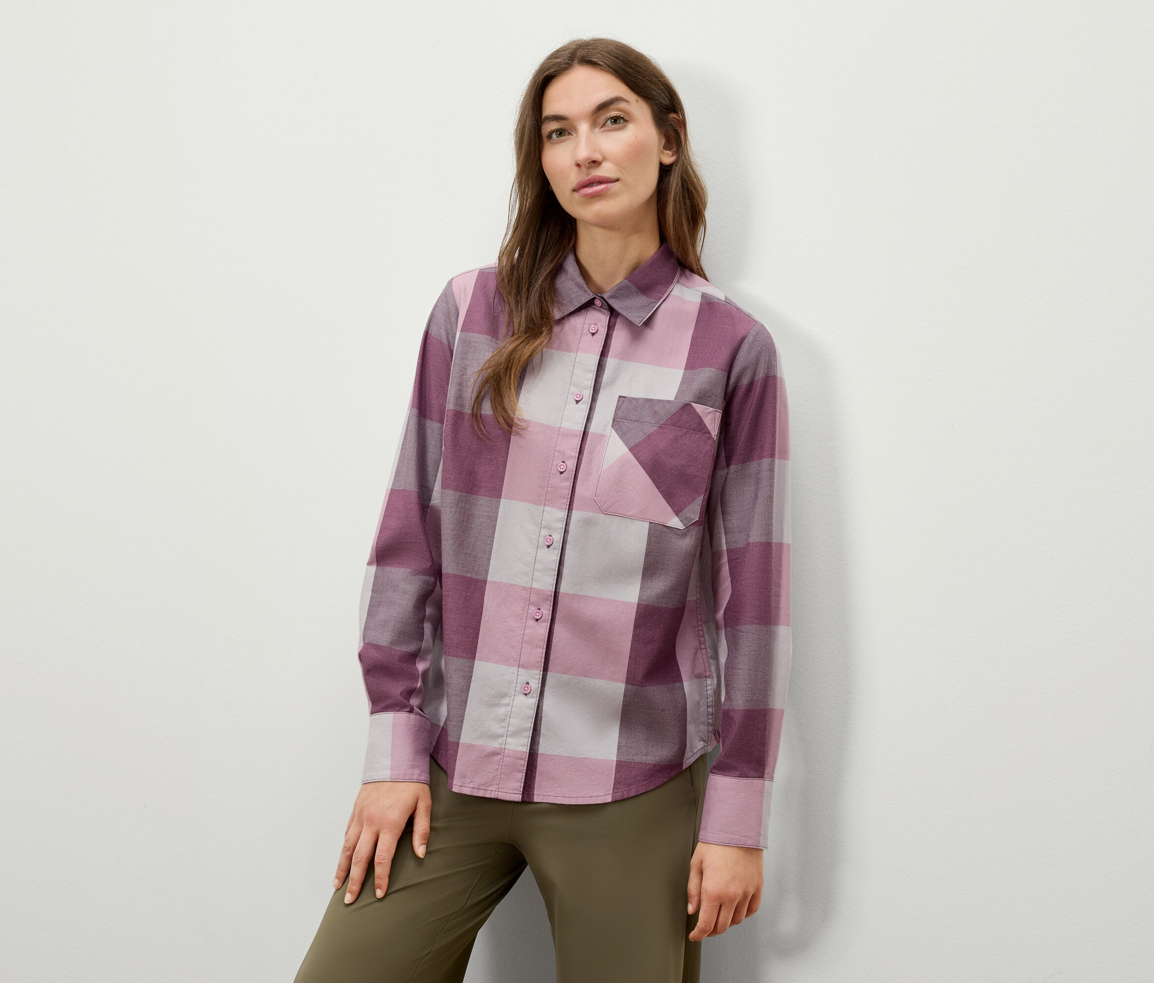 Femme posant dans une chemise à carreaux à manches longues et un pantalon vert olive.