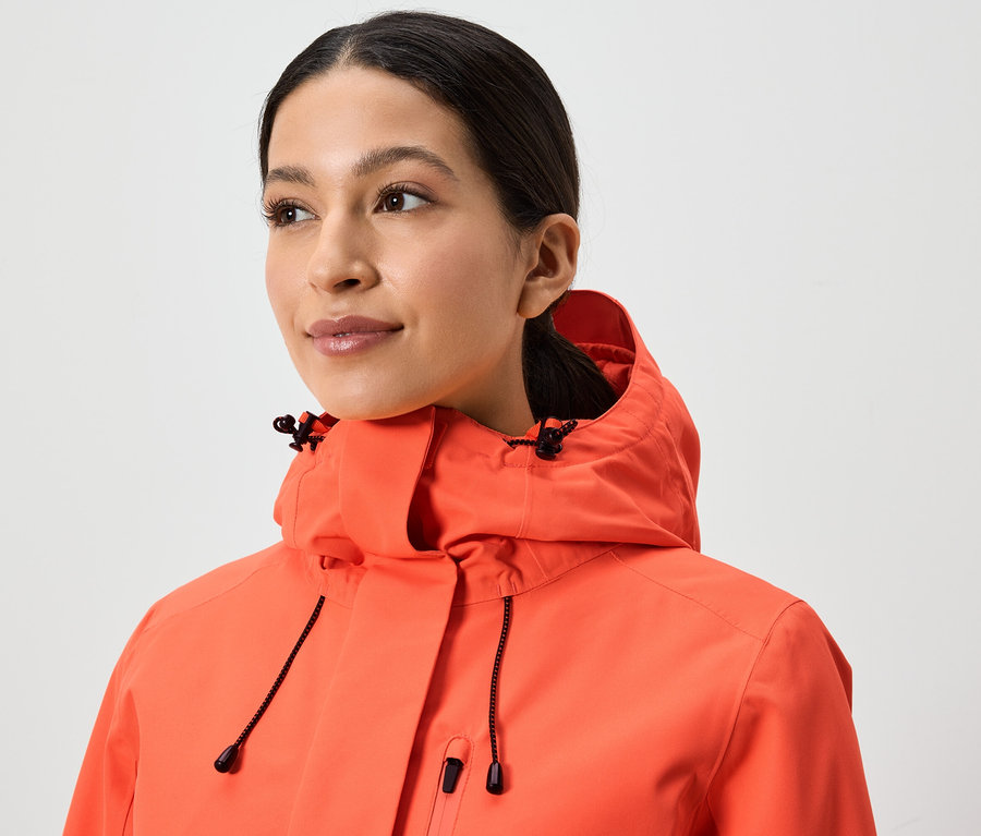Portrait d'une femme portant une veste corail à capuche.