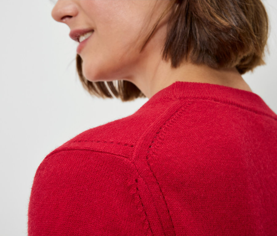 Gros plan d'une femme aux cheveux bruns courts portant un pull rouge.