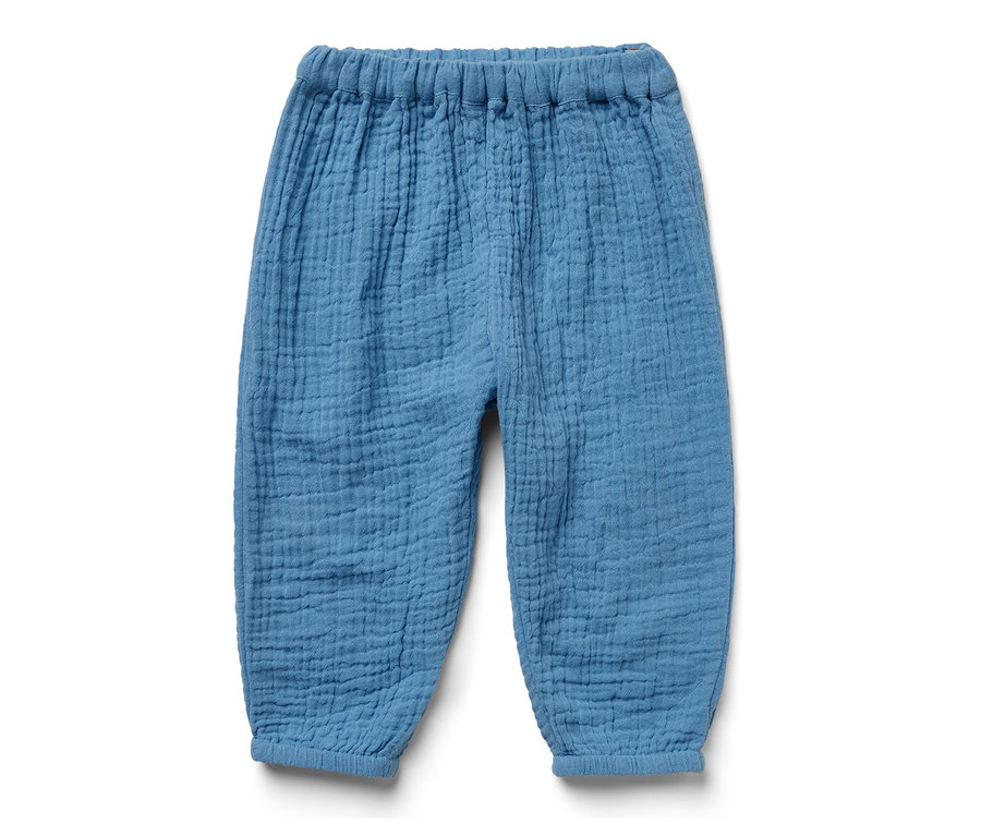 Un pantalon en mousseline bleu pour bébé sur fond blanc.