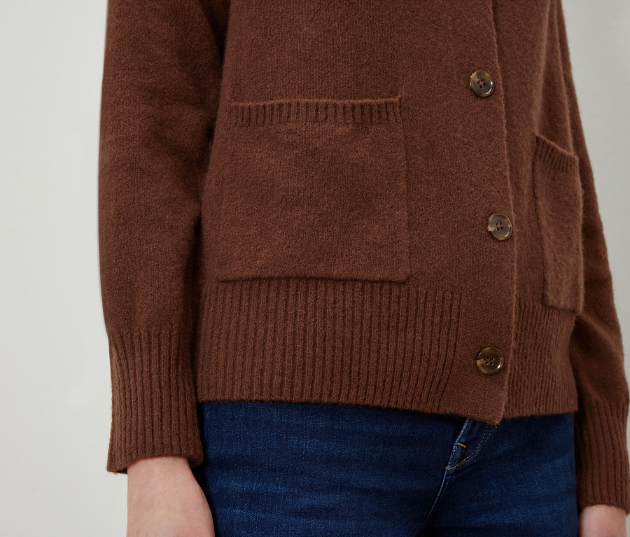Gros plan sur un cardigan marron avec des poches et des boutons.