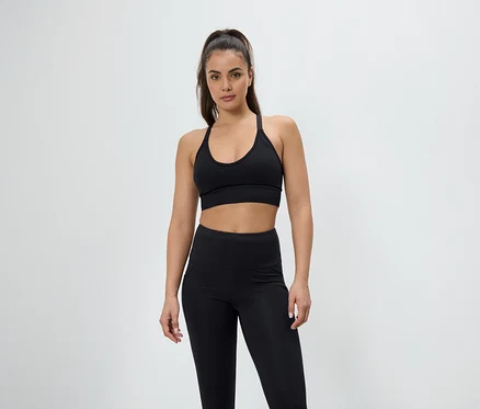 Femme posant en soutien-gorge de sport et leggings noirs.