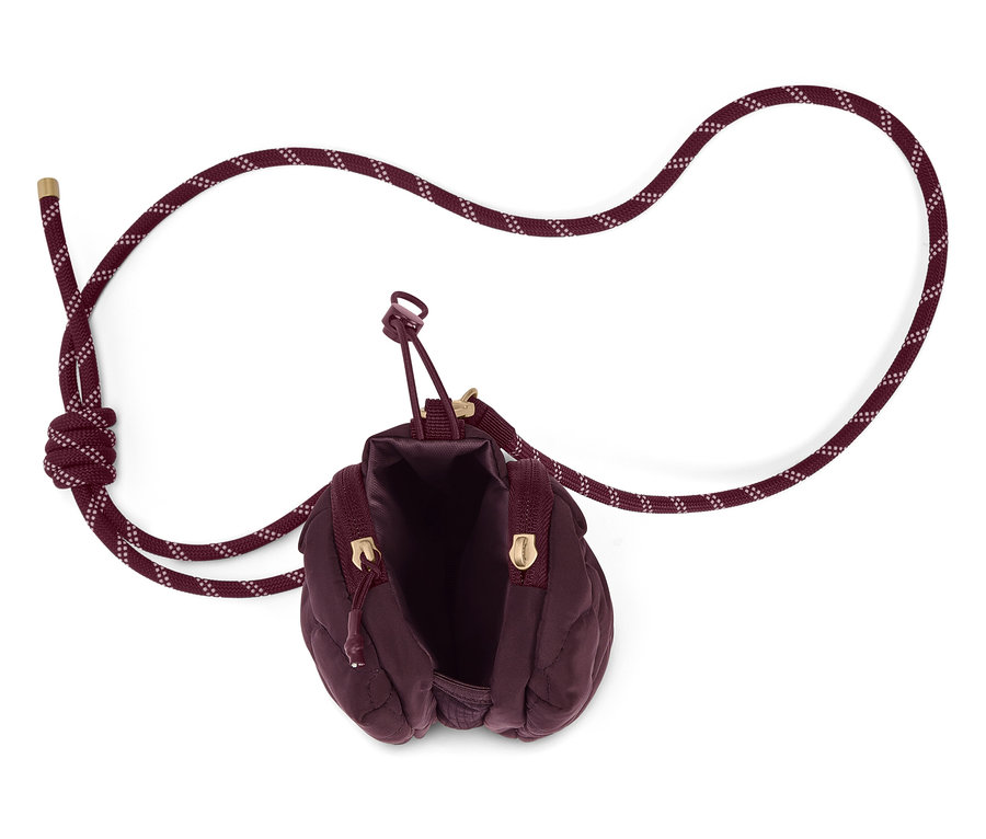 Vue de dessus d'un sac à main matelassé bordeaux ouvert avec une bandoulière en corde sur fond blanc.