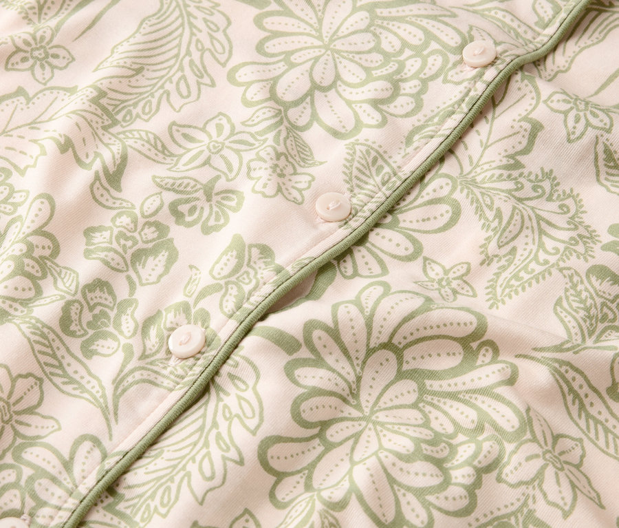 Gros plan sur un tissu rose clair à motif floral vert avec des boutons.