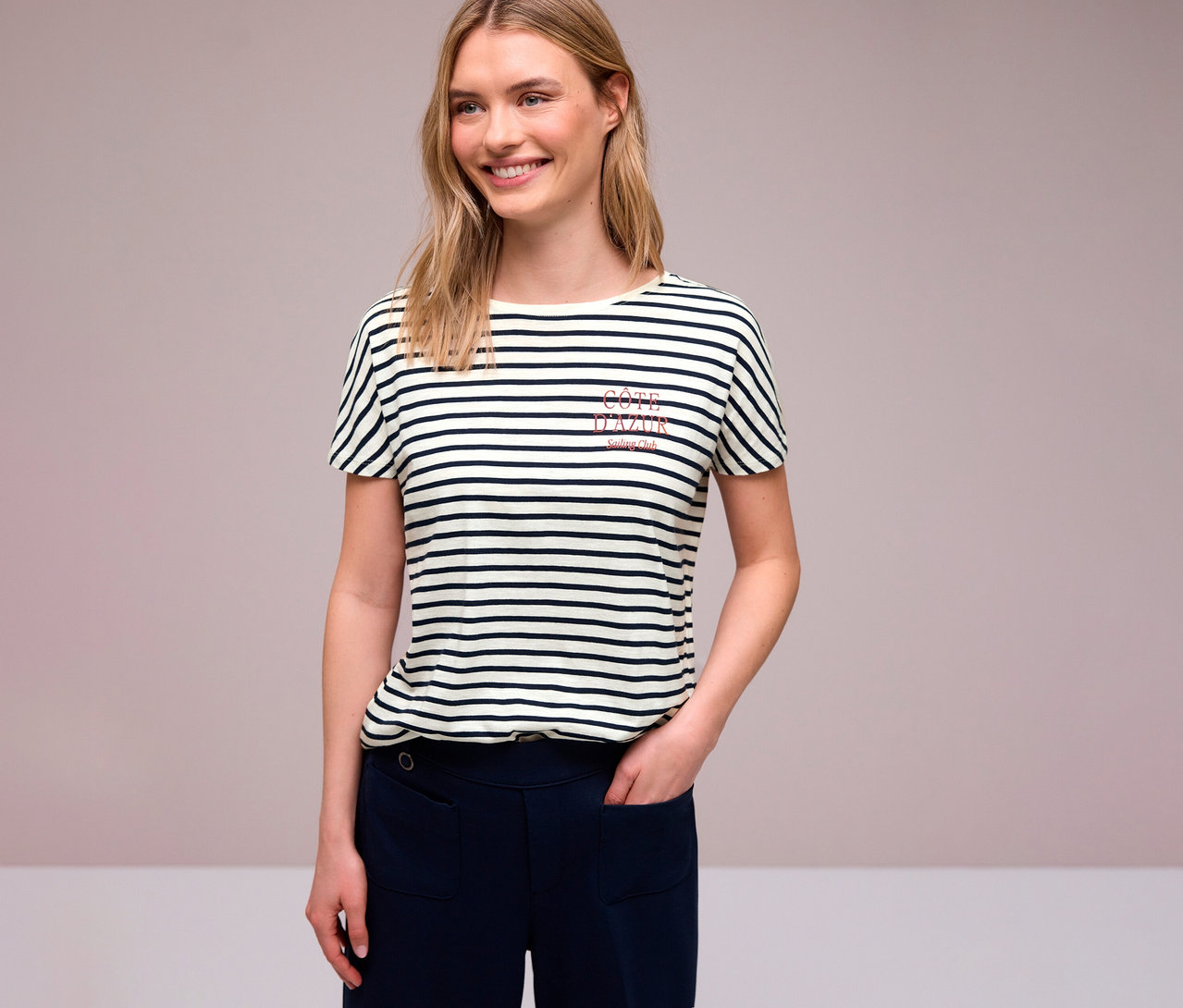 Une femme blonde porte un t-shirt Street One bleu marine et blanc à rayures et un pantalon bleu marine.