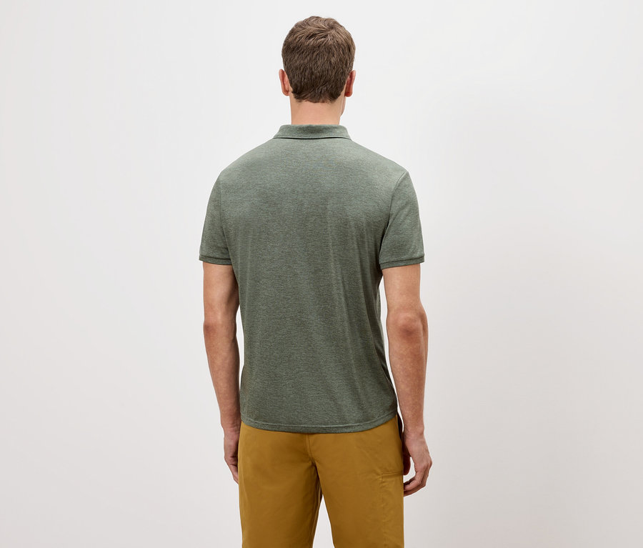 Vue arrière d'un homme portant un polo vert et un short doré sur un fond blanc.