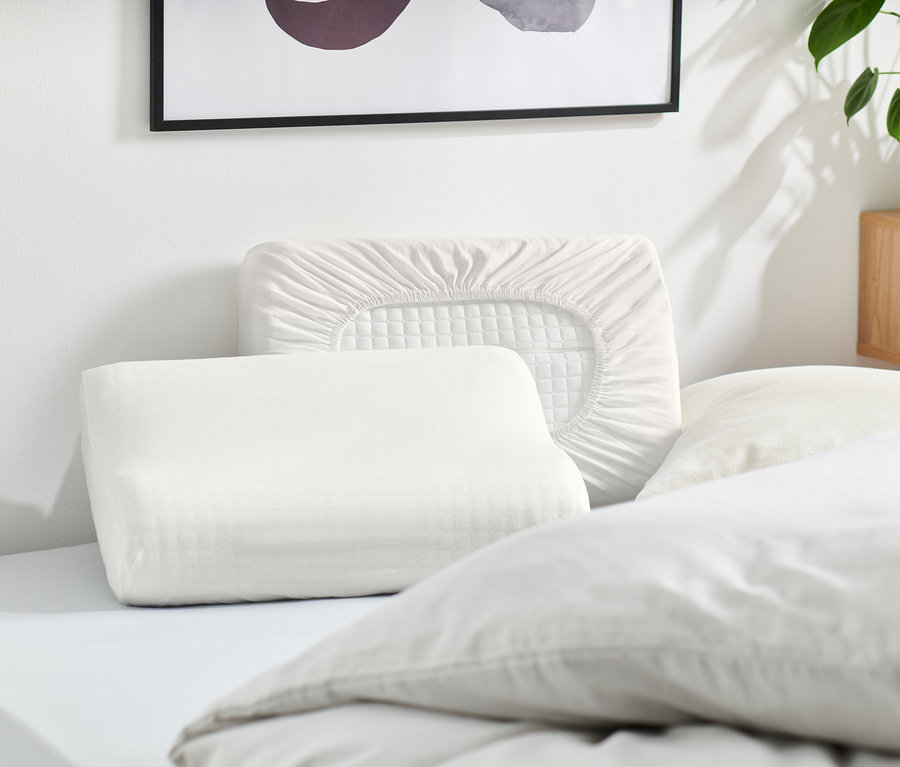 Plusieurs oreillers blancs et une taie d'oreiller blanche sont posés sur un lit.