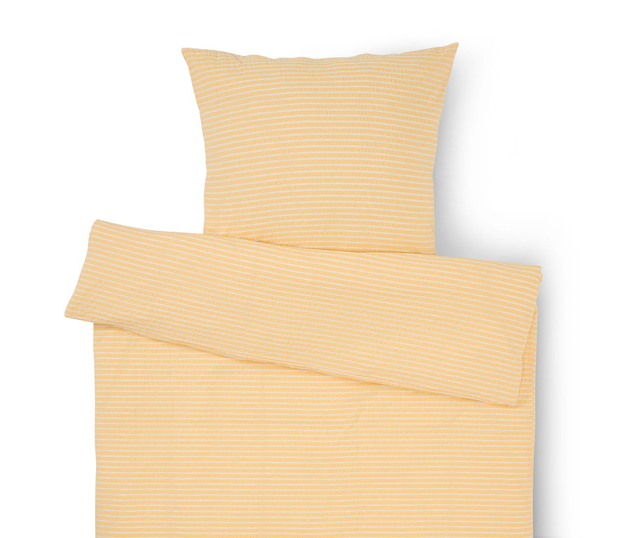 Linge de lit rayé jaune et blanc avec taie d'oreiller et couette partiellement repliée.