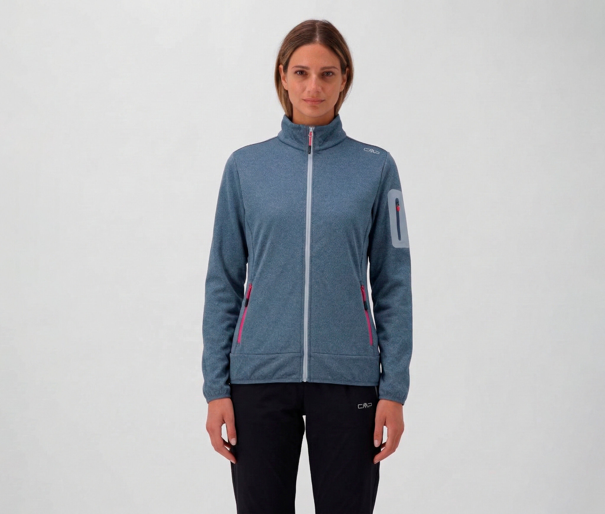 Femme portant un pantalon noir et une veste CMP pour femme bleue avec fermeture éclair et poches.