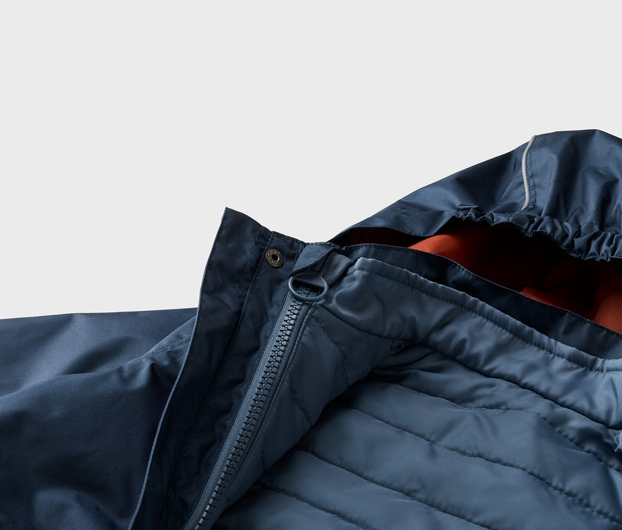 Gros plan d'une veste bleu marine ouverte avec capuche, fermeture éclair et doublure matelassée.