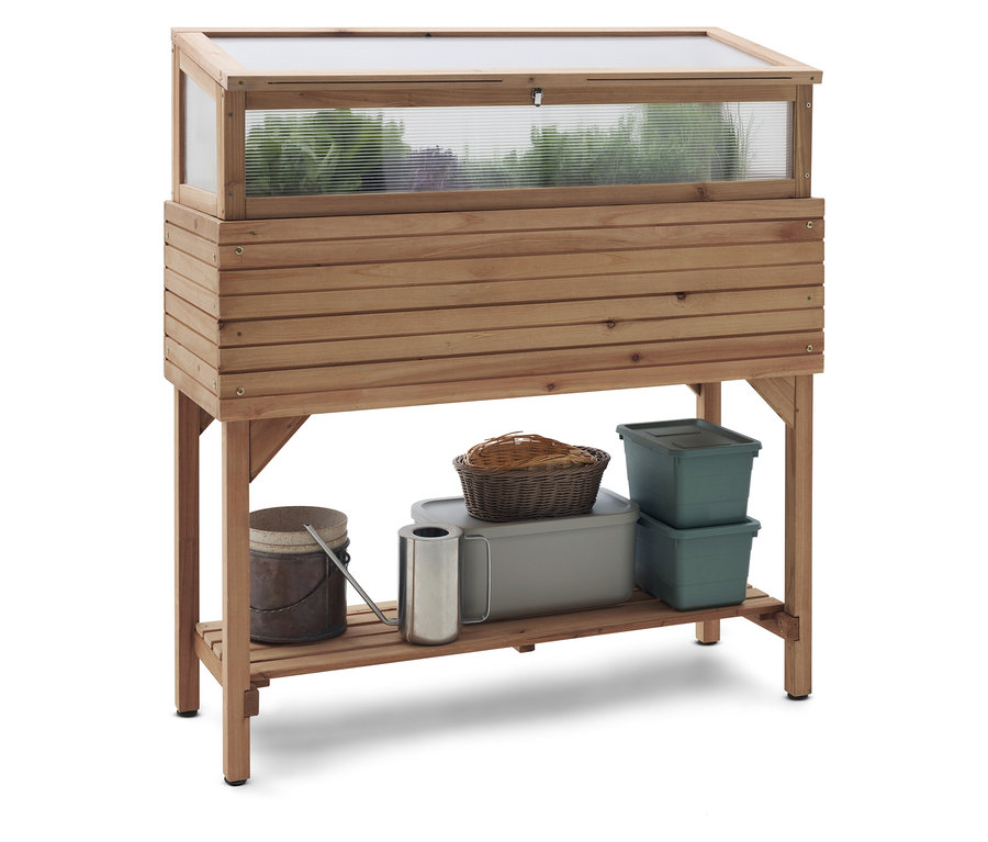 Jardinière surélevée en bois avec couvercle transparent et étagère contenant un arrosoir, un panier et des récipients.