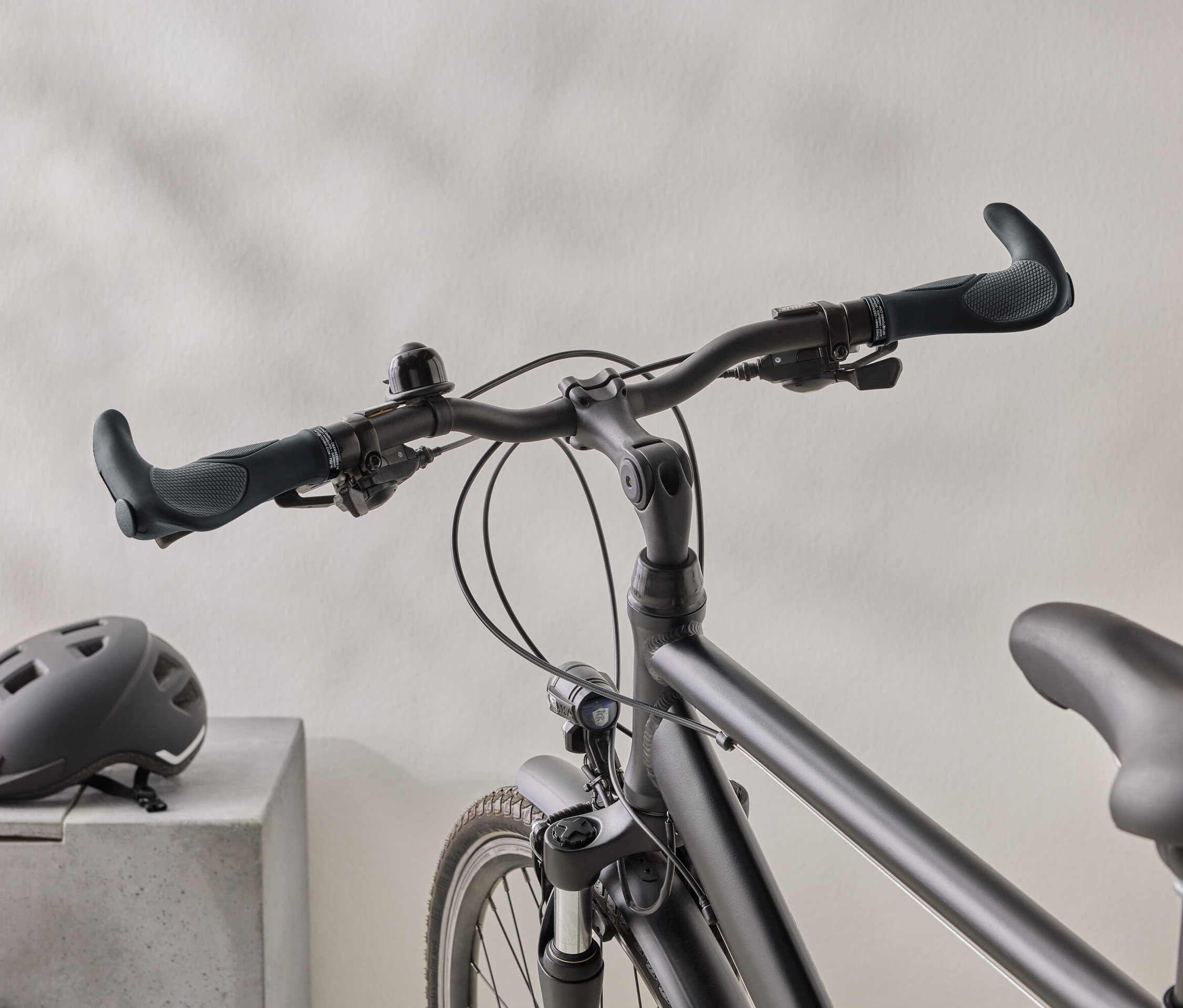 Gros plan d'un vélo noir mat avec un casque noir sur une surface en béton en arrière-plan.