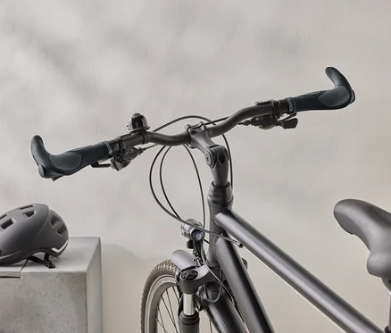 Gros plan d'un vélo noir mat avec un casque noir sur une surface en béton en arrière-plan.