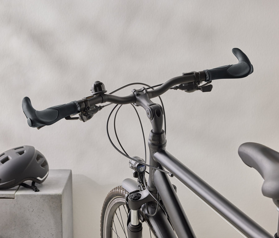 Gros plan d'un vélo noir mat avec un casque noir sur une surface en béton en arrière-plan.