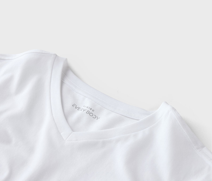 Gros plan d'un t-shirt blanc à col en V avec le logo Tchibo Every Body sur le col.