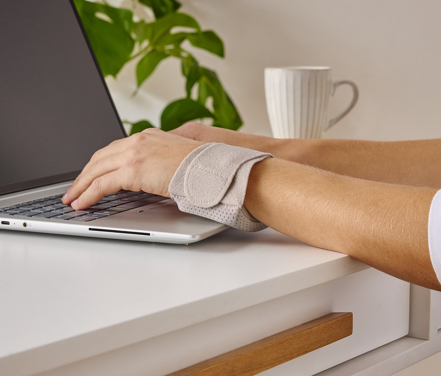 Personne tape sur un ordinateur portable et porte un support de poignet.