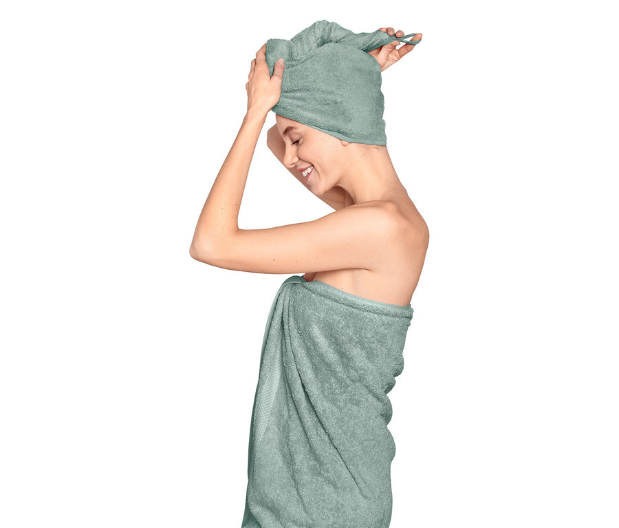 Femme enroulant une serviette bleu clair autour de sa tête et de son corps.