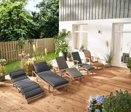 Plusieurs chaises longues de jardin et un fauteuil de jardin Adirondack avec repose-pieds extensible en bois sont disposés sur une terrasse en bois.