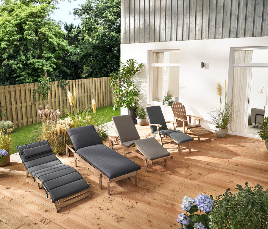 Plusieurs chaises longues de jardin et un fauteuil de jardin Adirondack avec repose-pieds extensible en bois sont disposés sur une terrasse en bois.