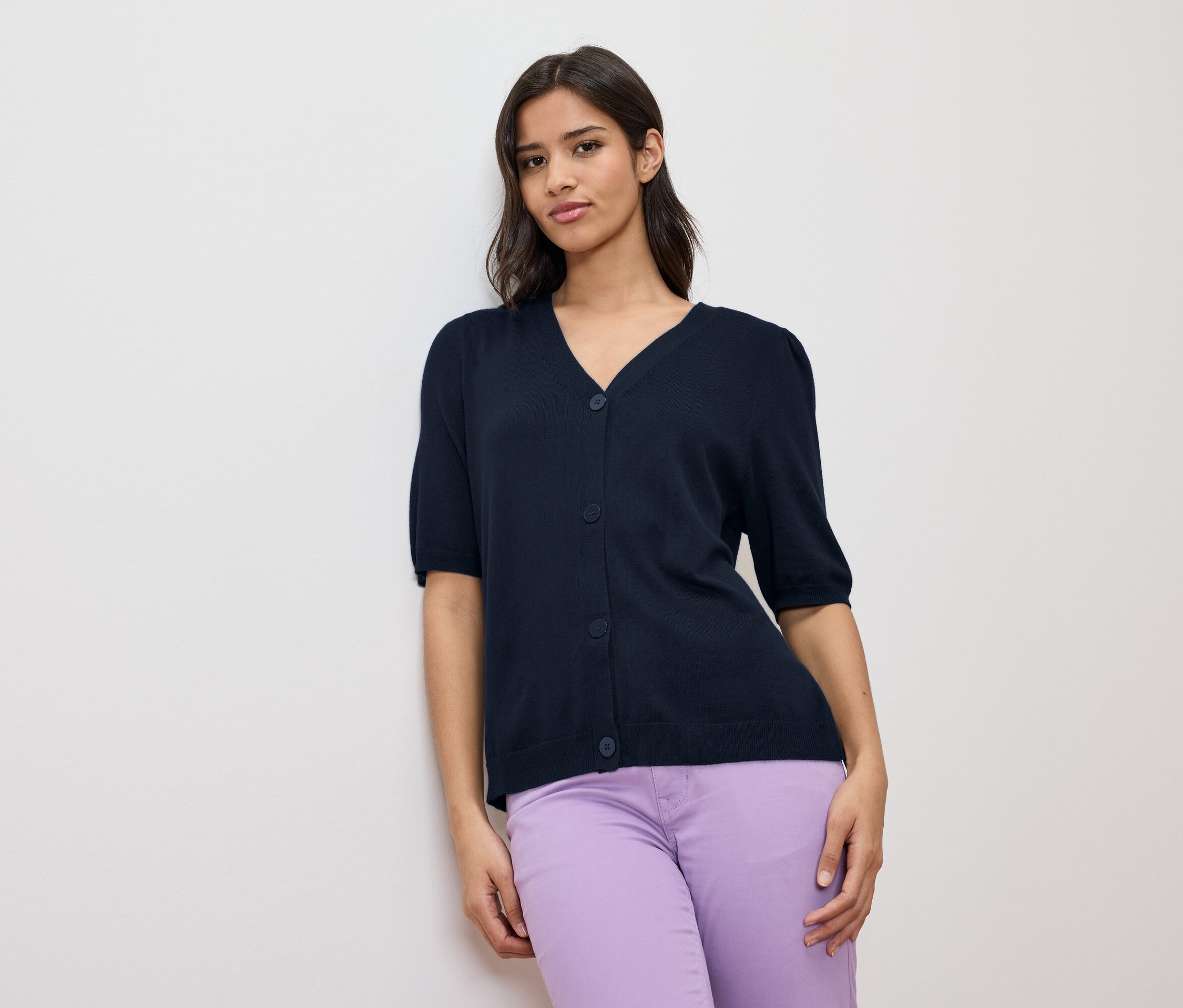 Femme portant un cardigan bleu marine à manches courtes et un pantalon violet.
