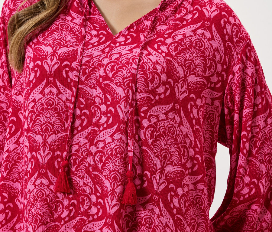 Gros plan d'un haut rouge à motif floral rose avec cordon de serrage.