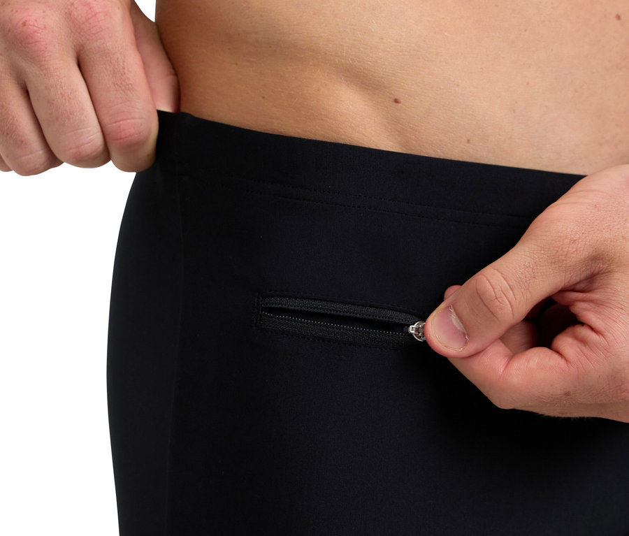 Un homme ouvre la fermeture éclair d'un pantalon noir.