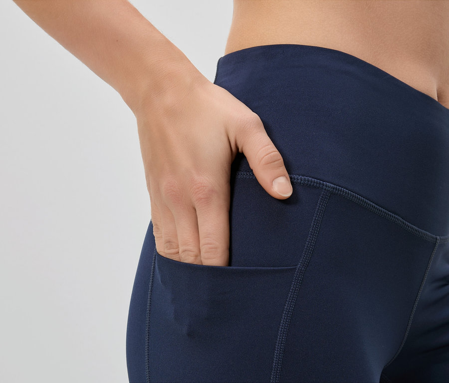Femme mettant sa main dans la poche d'un legging bleu marine.