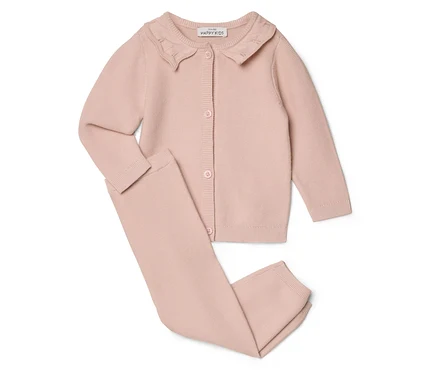 Un cardigan rose à col et un pantalon sont posés sur un fond blanc.