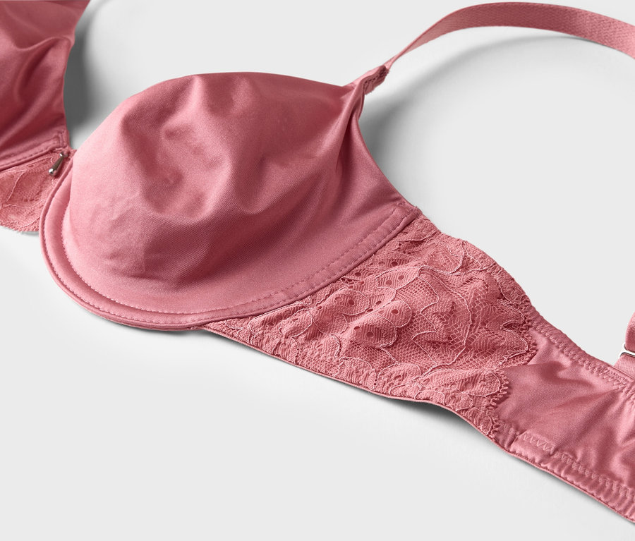 Gros plan d'un soutien-gorge rose avec de la dentelle et des bretelles réglables sur fond blanc.