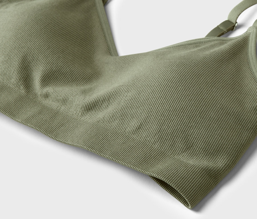 Gros plan d'une brassière de sport vert olive côtelée avec des bretelles réglables sur un fond neutre.