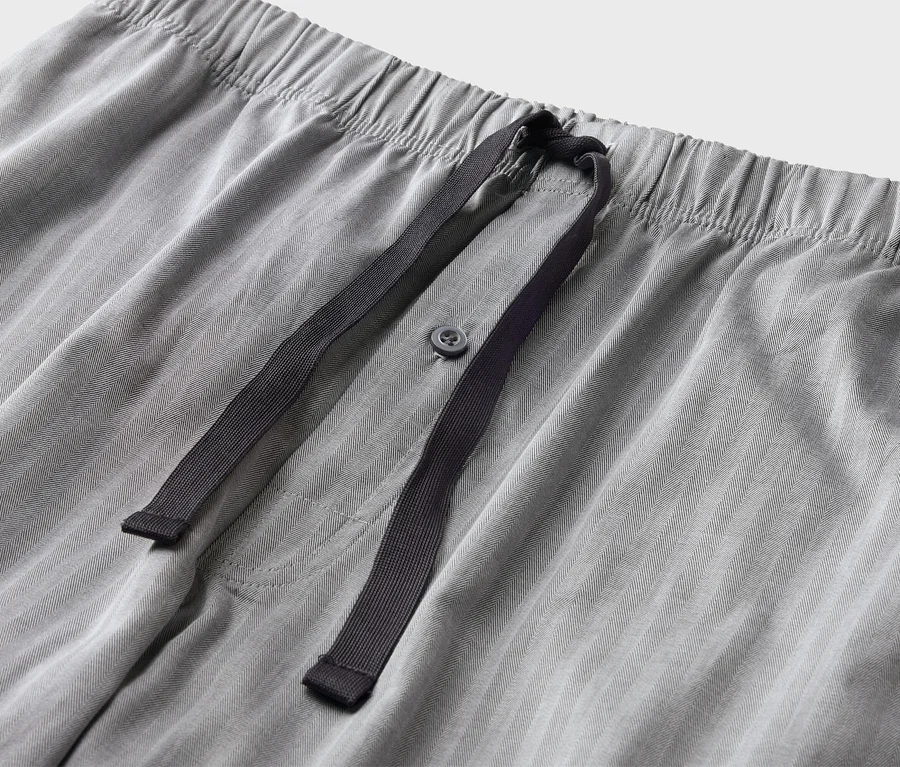 Gros plan d'un pantalon gris avec cordon de serrage et bouton.