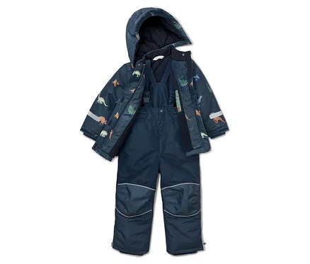 Combinaison de ski bleu marine à motif de dinosaures, veste ouverte à capuche et pantalon à bretelles posés au sol.