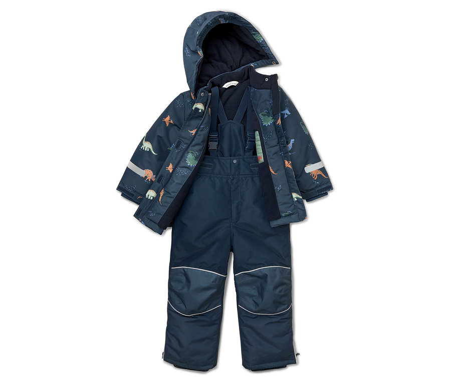 Combinaison de ski bleu marine à motif de dinosaures, veste ouverte à capuche et pantalon à bretelles posés au sol.
