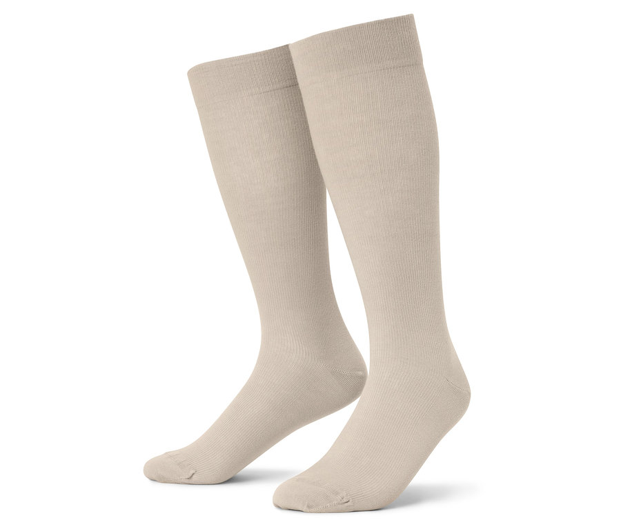 Gros plan de deux chaussettes montantes beiges sur fond blanc.